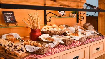 A bakery display with various breads and pastries, including a sign with a humorous message.