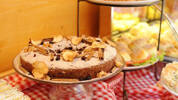 A dessert display with a variety of cakes and pastries on a red and white checkered tablecloth.