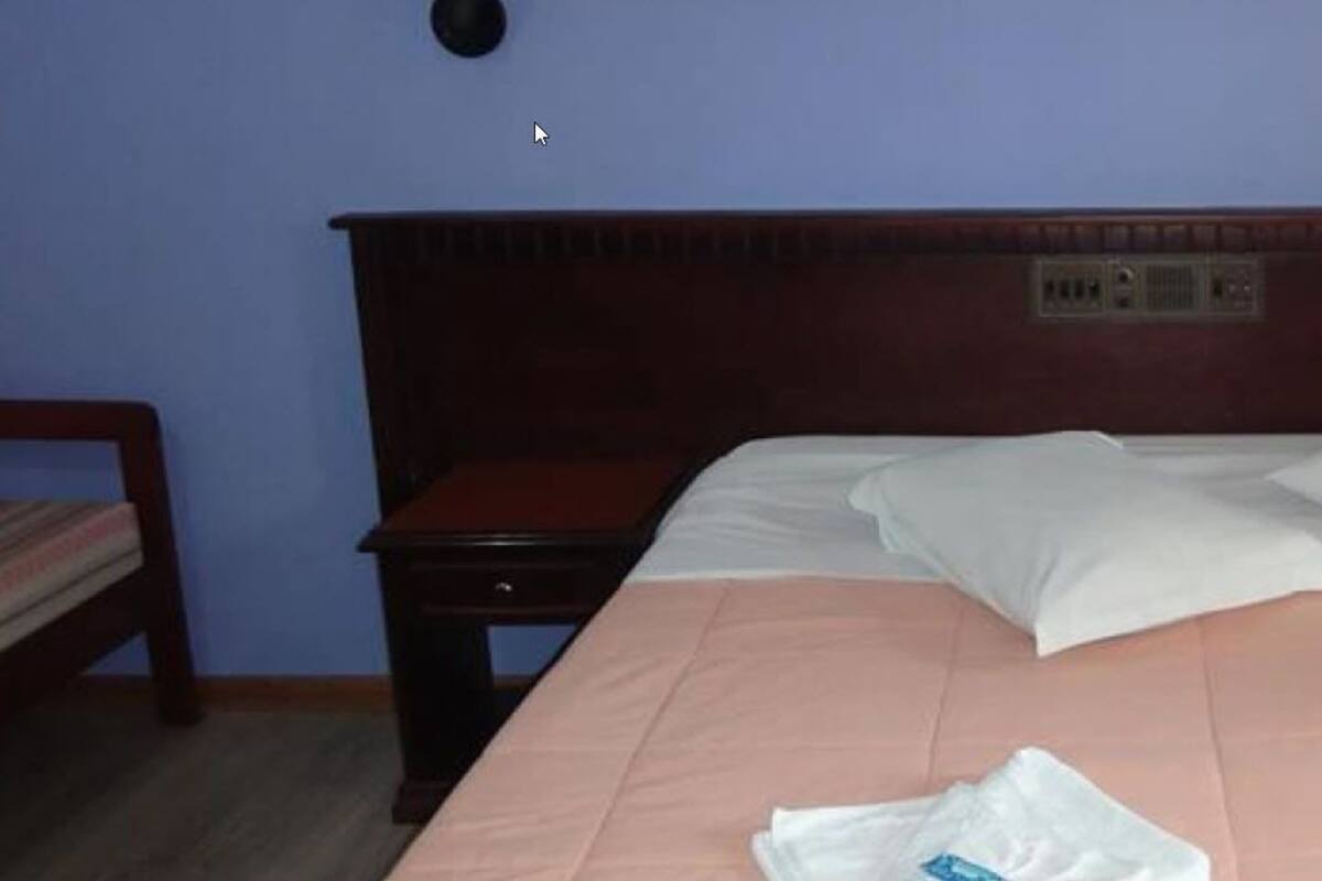 A bed with white linens, a wooden headboard, and two bedside tables.