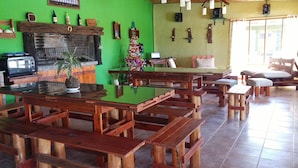 Un coin repas rustique avec des bancs et des tables en bois, une cheminée en briques et un mur végétal agrémenté de diverses décorations.