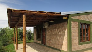 Un bâtiment de style rustique, avec une façade en briques, une porte en bois et un patio couvert.