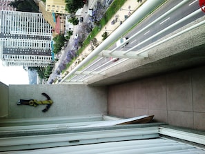 A view of a building's exterior with a metal staircase, a concrete wall, and a row of purple flowers.