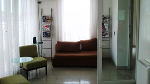Una sala de estar con un sofá marrón, una mesa de vidrio y un sillón verde.