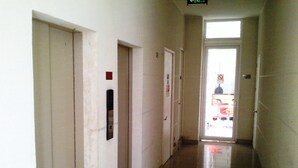Un pasillo limpio y bien iluminado con suelo de baldosas, puertas y un cartel que indica la salida.