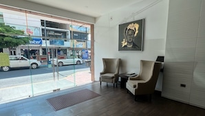 Un interior moderno con una zona de recepción, dos sillones de cuero, un ventanal grande y una obra de arte colgada en la pared.