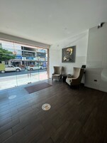 A modern interior with a reception area, two leather chairs, a large window, and a wall-mounted artwork.