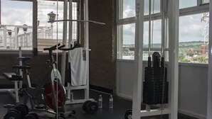 A gym with various exercise equipment, large windows, and a view of the outside. - Hotel Latino (Sahuayo)
