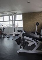 A gym with weightlifting equipment, a bench, and a bike in the background.