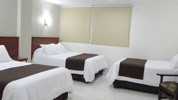 Habitación de hotel con dos camas individuales, cabecero de madera, una silla y una ventana con persianas.
