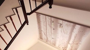 A staircase with a wooden handrail leading to a landing with a skylight. - Wo House (Puli)