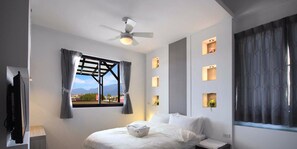 Relax in a serene space with a large bed, ceiling fan, and stunning mountain views.