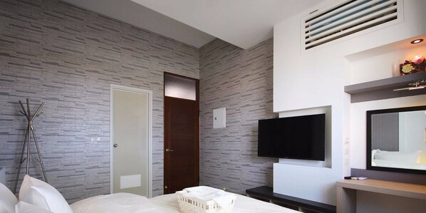 A modern hotel room with a stone-patterned wall, a wooden door, a flat-screen TV, a bedside table, and a large mirror. - Wo House (Puli)
