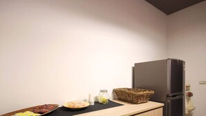A kitchen with a refrigerator, a wooden countertop, a basket, and a bowl of food. - Wo House (Puli)