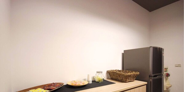 Une cuisine équipée d’un réfrigérateur, d’un plan de travail en bois, d’un panier et d’un saladier rempli de nourriture.