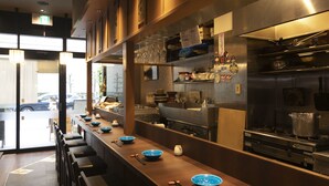 A modern kitchen with stainless steel appliances, a long counter with blue bowls, and a seating area with chairs.