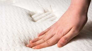 A hand resting on a textured white surface, likely a bed or couch.