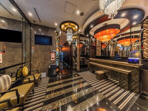 A hotel lobby with a reception desk, seating area, and a chandelier.