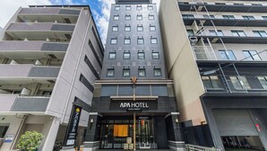 A modern hotel with a prominent entrance, multiple balconies, and a clear sky.
