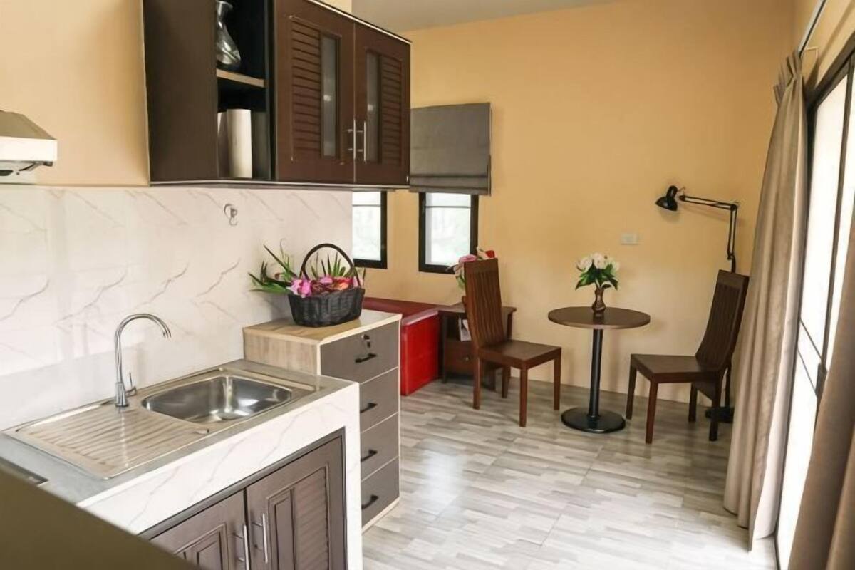 A compact kitchen with a sink, cabinets, a small dining area with a table and chairs, and a window providing natural light.