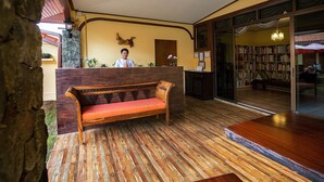 A reception area with a wooden bench, a receptionist, and a bookshelf filled with books. - Taratai Villa (Pattaya)