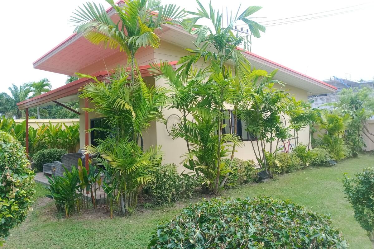 A house with a red roof, surrounded by lush greenery and a well-maintained lawn.