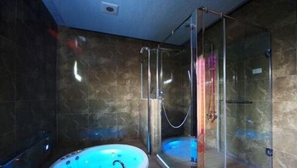 Un baño moderno con ducha envuelta en vidrio, bañera y zona de ducha independiente.