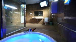 A bathroom with a large bathtub, a glass shower enclosure, a toilet, and a sink. - Cherry Blossom Motel (Puli)