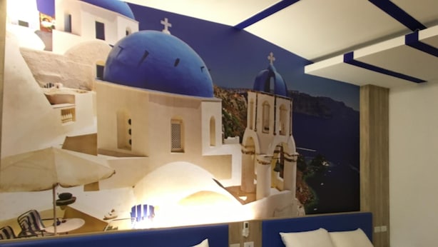 A hotel room with a mural of a blue-domed building, a bed with white and brown bedding, and a blue headboard. - Cherry Blossom Motel (Puli)