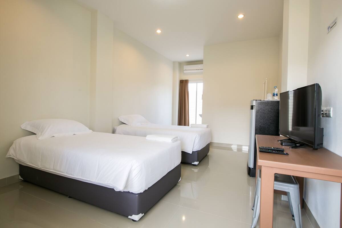 A hotel room with two beds, a TV, and a desk.