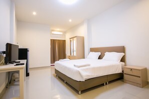 A modern hotel room with a large bed, a desk with a computer, and a wardrobe. - J-House Phetchaburi (Phetchaburi)