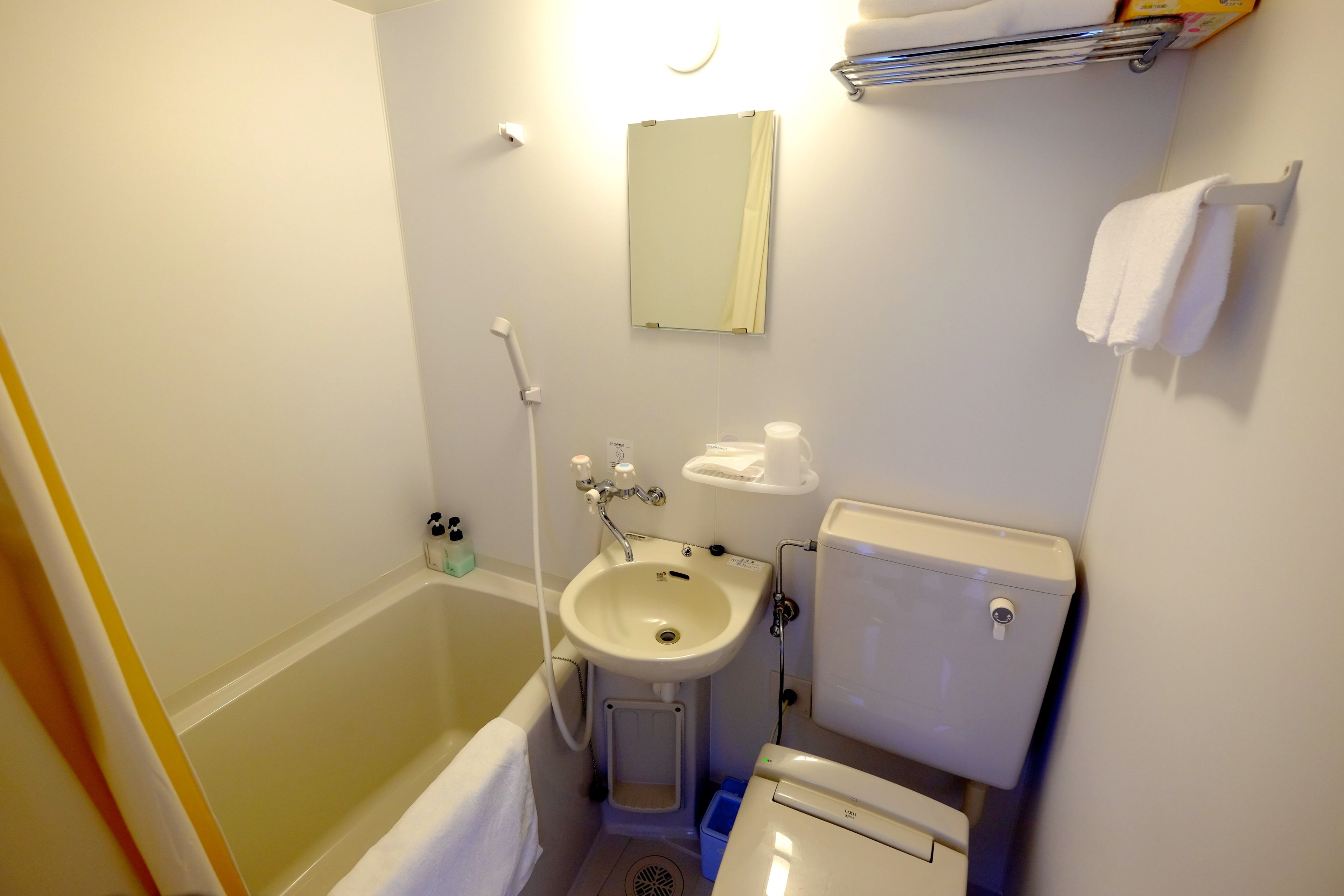A small bathroom with a bathtub, sink, toilet, and a mirror.
