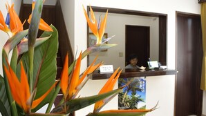 A reception desk with a sign reading "Front Desk" and a poster of a tropical scene. - Lodge Ocean (Hachijo)