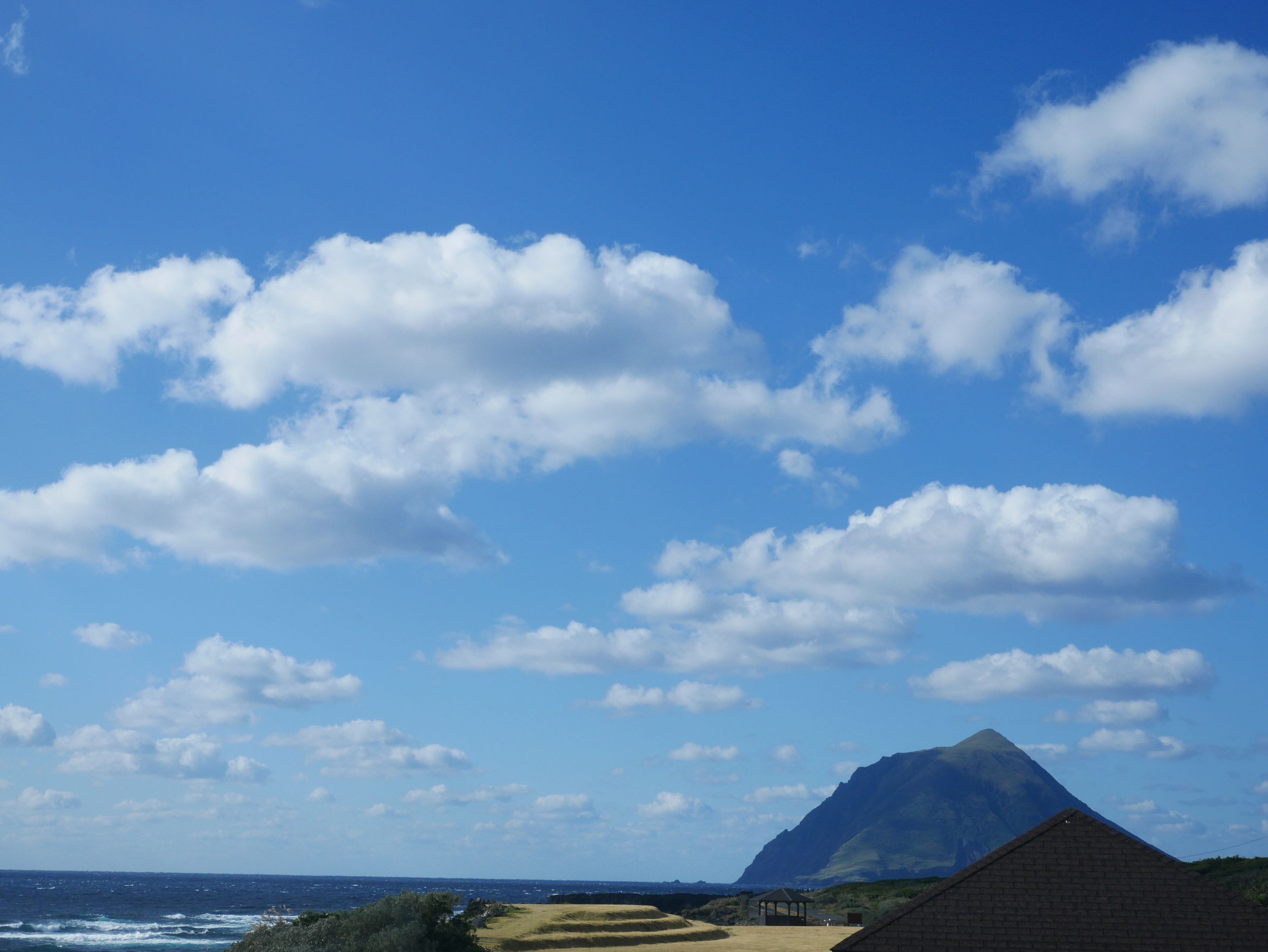 Un paysage côtier comprenant une montagne, une plage et un pavillon.