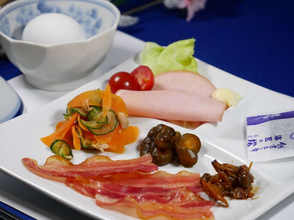 A plate with various foods including sliced meat, vegetables, and a small packet of seasoning.