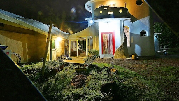 A unique, modern building with a circular structure, a small entrance with a red door, and a well-lit interior. - Moonlight Pension (Seogwipo)