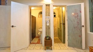 A hotel entrance with a tiled floor, a small wooden table with a plant, and a bathroom visible through the open door. - Moonlight Pension (Seogwipo)