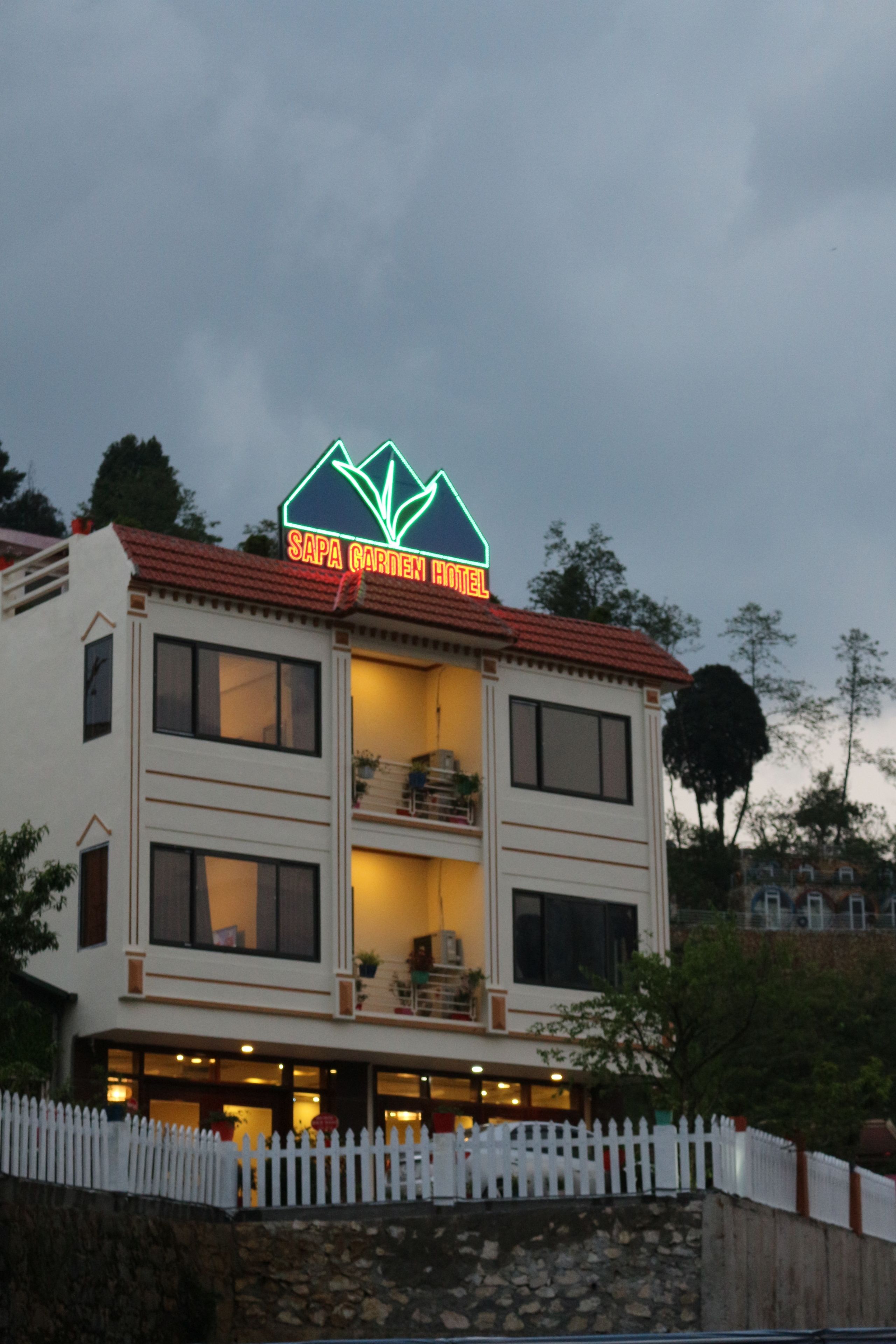 Un bâtiment à deux étages sur lequel on peut lire l’inscription « HÔTEL SAPA GARDEN ».