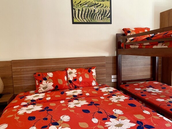 A room with a bunk bed and a single bed, both with floral bedding. - Sapa Garden Hotel (Sa Pa)