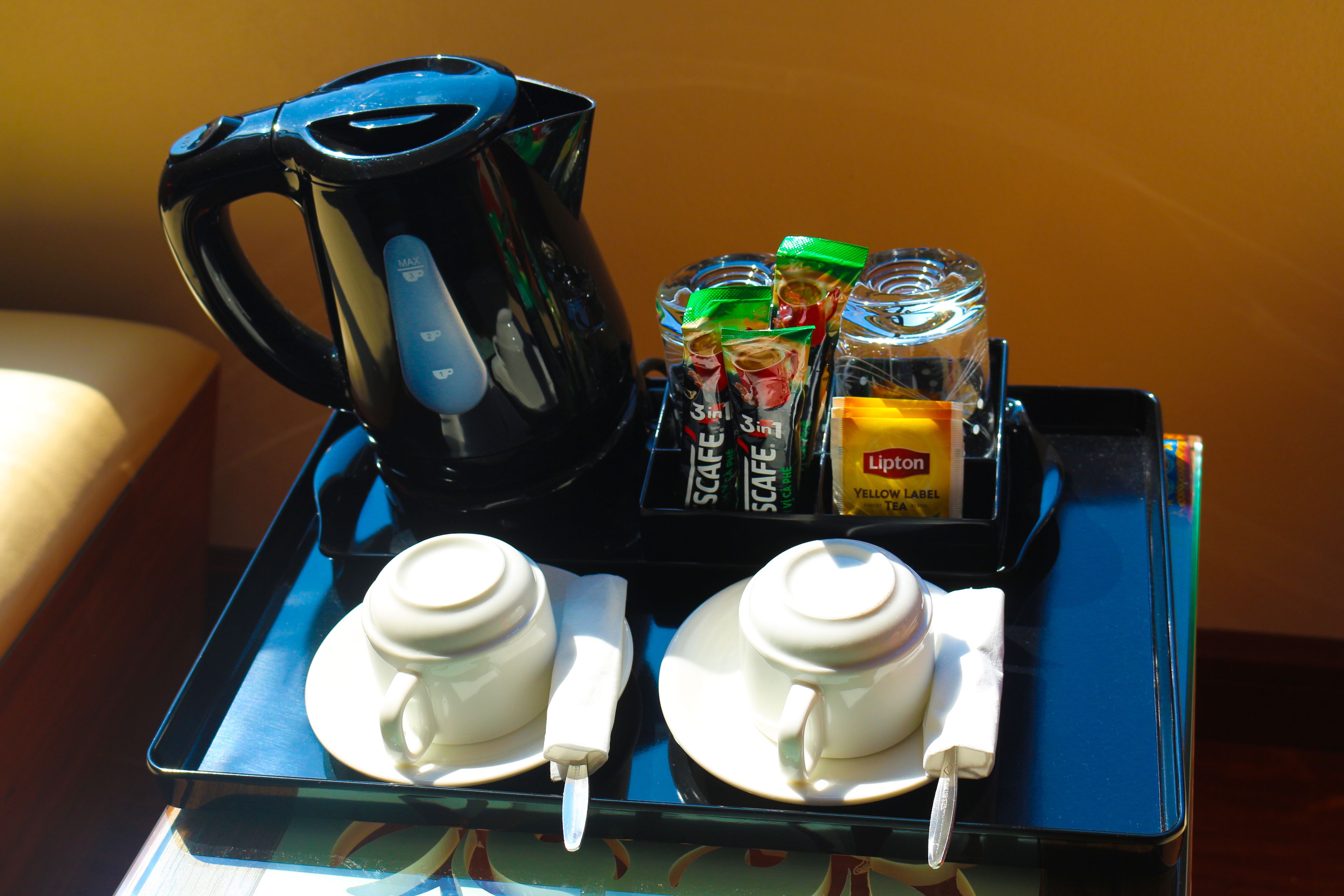 A tray with a coffee maker, two cups, sugar packets, and a Lipton tea packet.