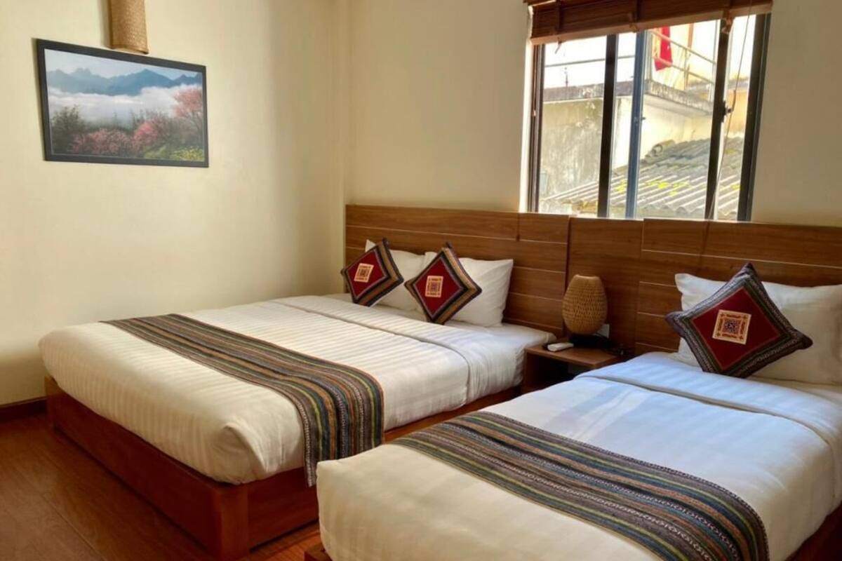 Ett hotellrum med två sängar, en sänggavel i trä, ett fönster med utsikt och en inramad tavla på väggen.