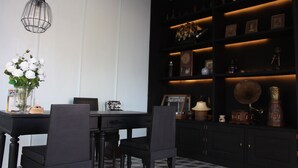 Un área de comedor con una mesa, sillas, un florero y una estantería con diversos objetos.