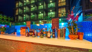 A hotel exterior at night with a bar area displaying various liquor bottles. - Aspira Residences Samui (Koh Samui)