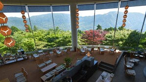 Un amplio espacio exterior con comedor y vistas a las montañas, muebles de madera y lámparas colgantes.
