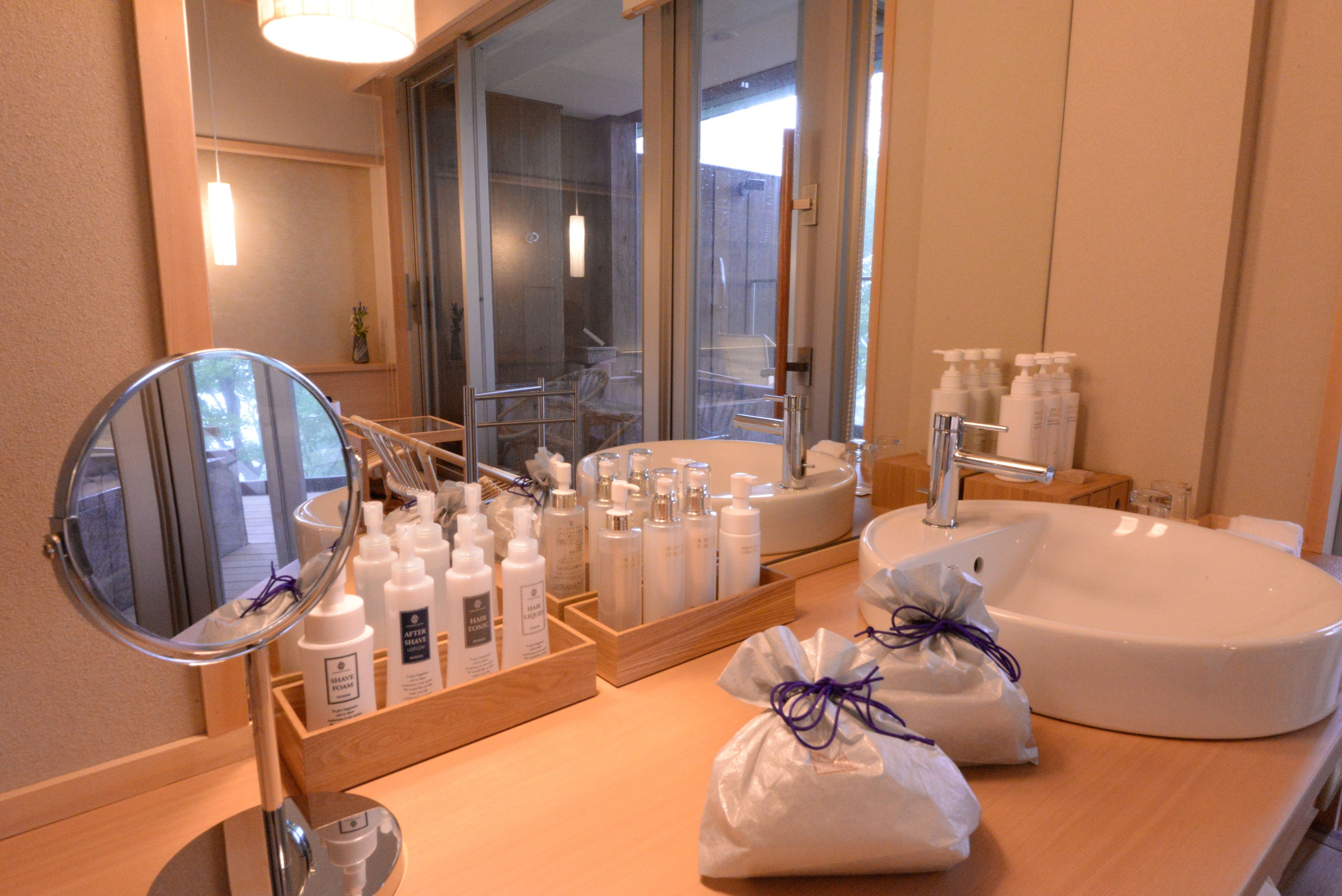 A bathroom with a large mirror, a sink, and various toiletries.