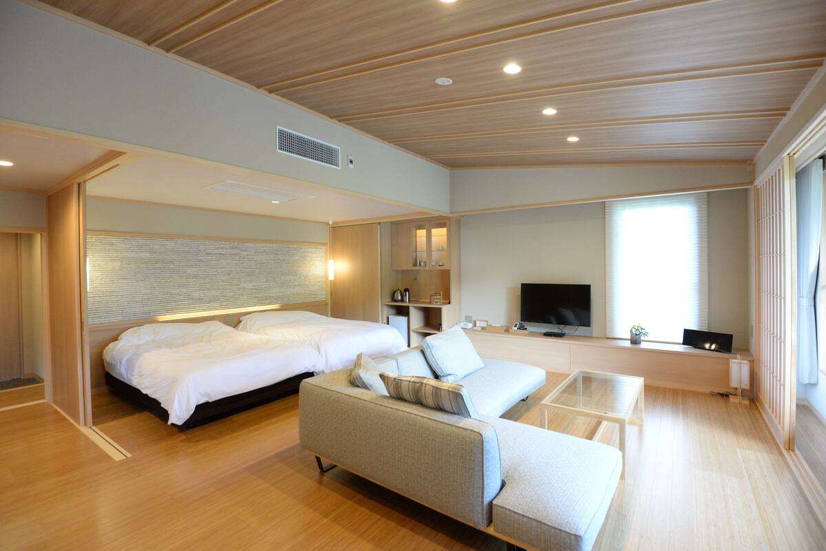 Una habitación de hotel moderna con una cama grande, un sofá, un televisor y un escritorio.