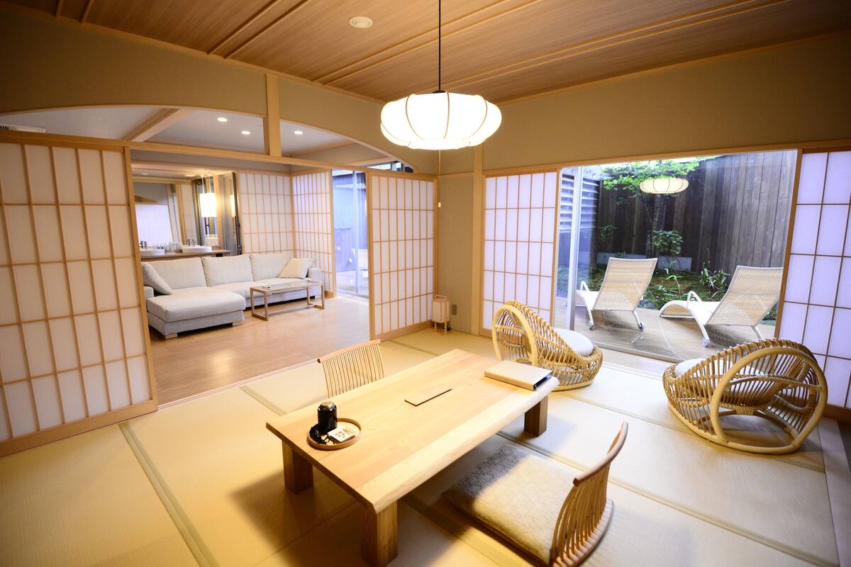 Una habitación tradicional japonesa con suelo de tatami, una mesa de madera baja y sillas tejidas.
