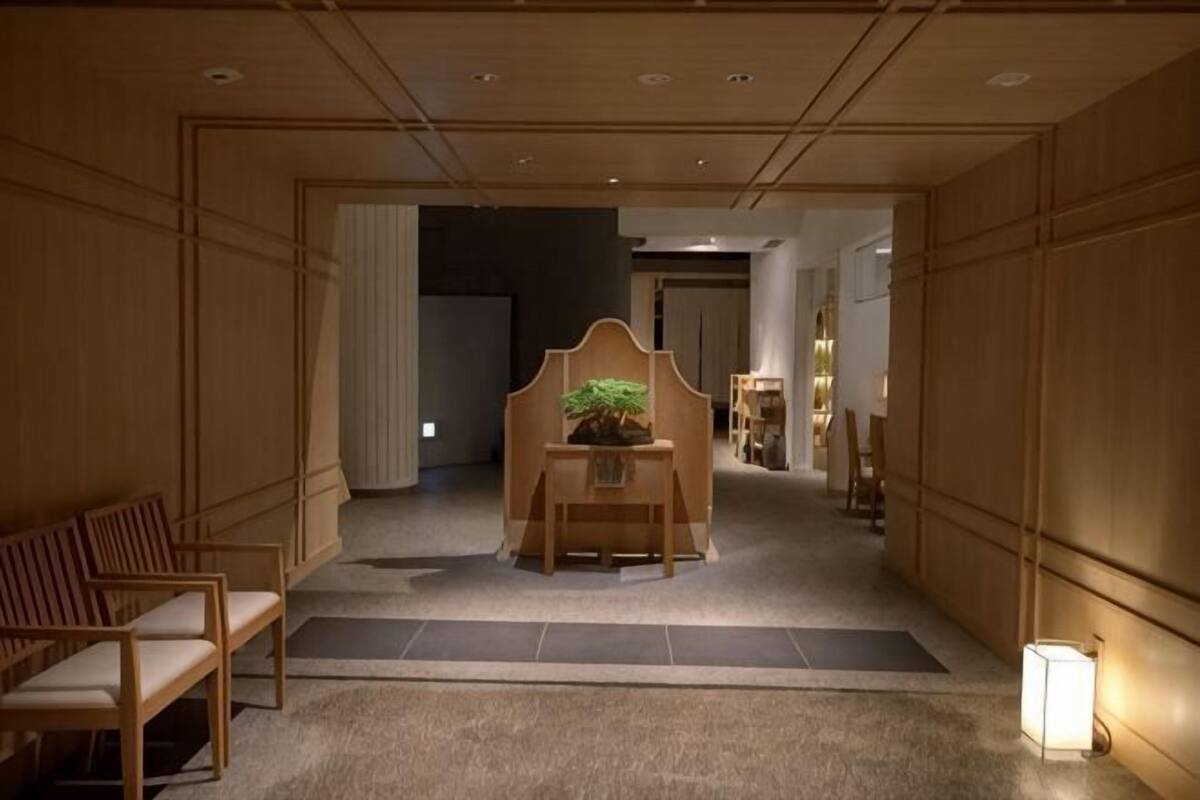 Un pasillo con paneles de madera, un mostrador de recepción con una planta y un área de estar con sillas.