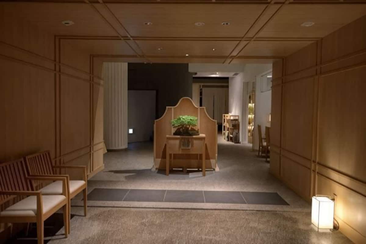 Un pasillo con paneles de madera, un mostrador de recepción con una planta y un área de estar con sillas.