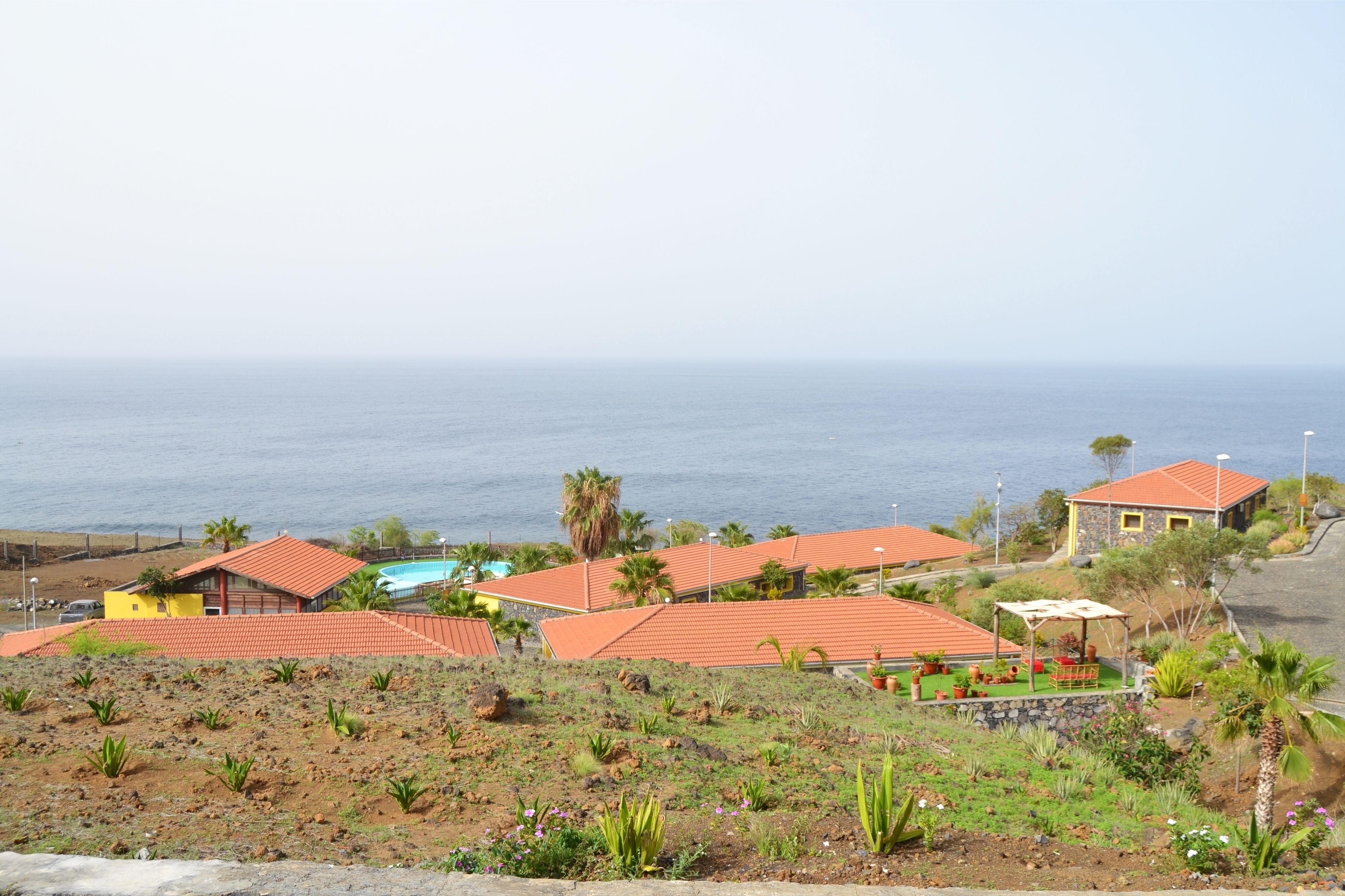 Une propriété située sur la côte, comprenant plusieurs bâtiments, une piscine et offrant une vue sur la mer.