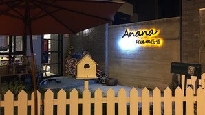 Una valla de madera, una casita de madera y un letrero de neón con caracteres chinos.
